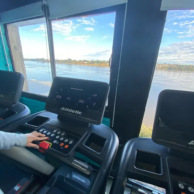 Consola de una cinta de correr frente al ventanal, con el río Uruguay de fondo